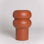 Terracotta-colored vase with a unique design on a white background