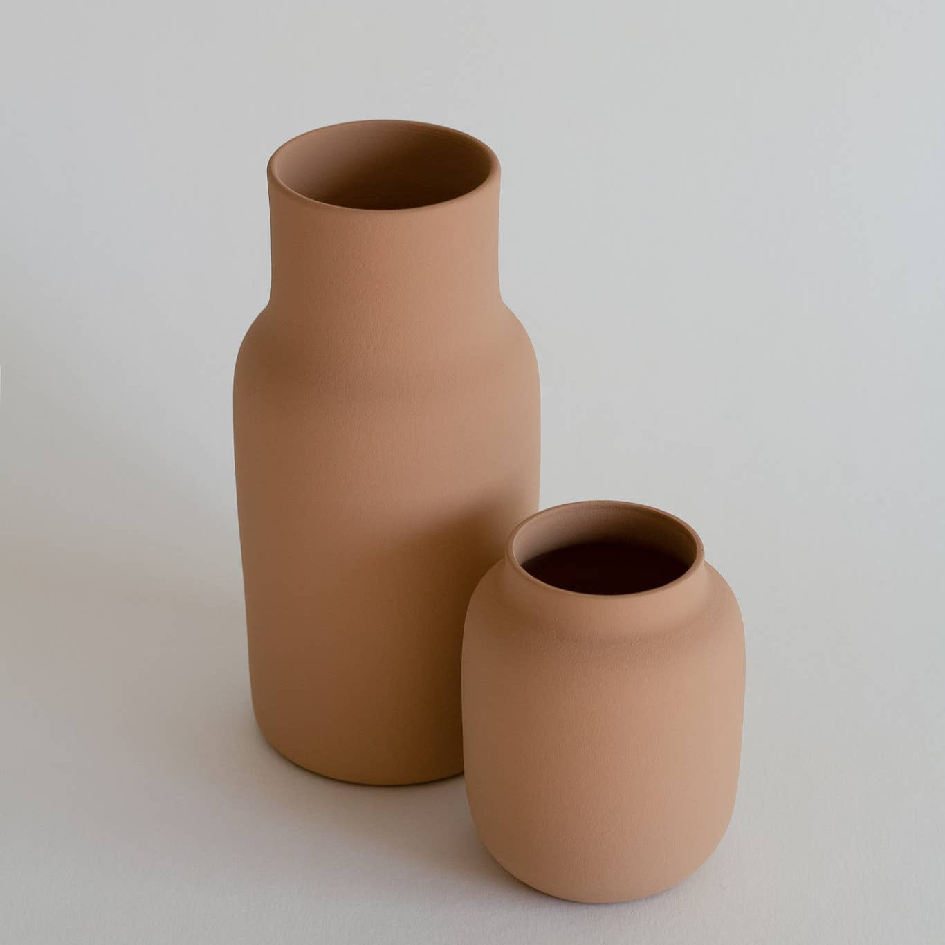 Two terracotta vases on a light gray background