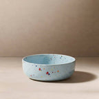 Speckled blue ceramic bowl on a beige background