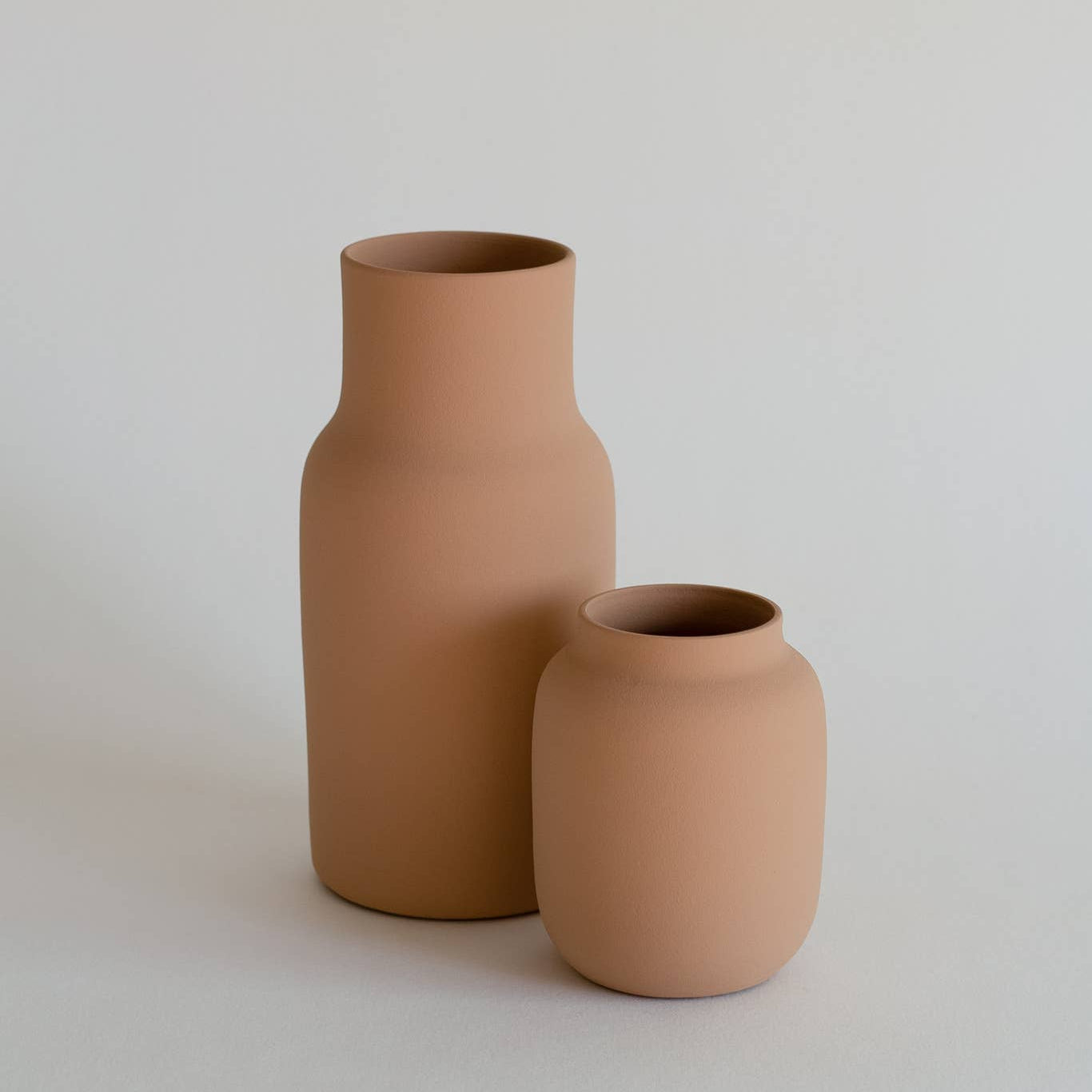 Two terracotta vases on a light gray background
