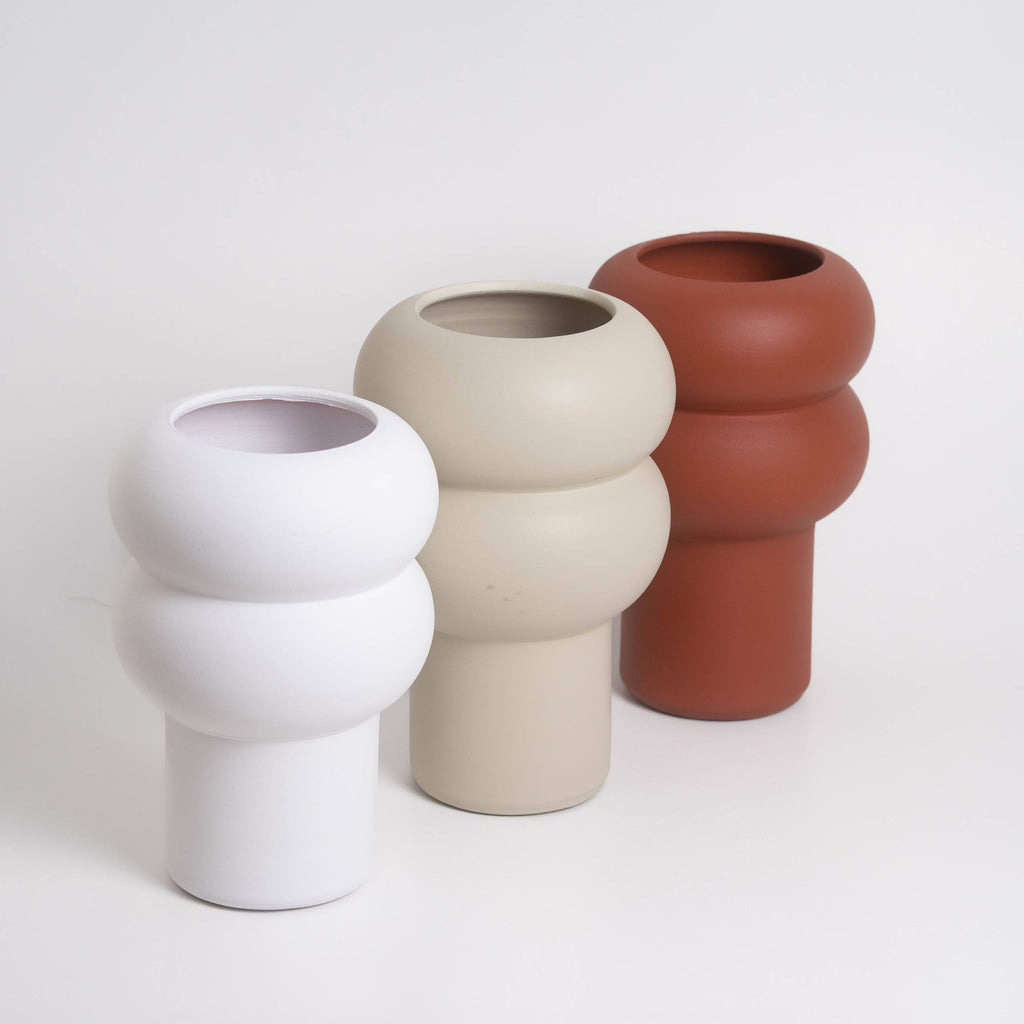 Three ceramic vases in white, beige, and terracotta on a light gray background
