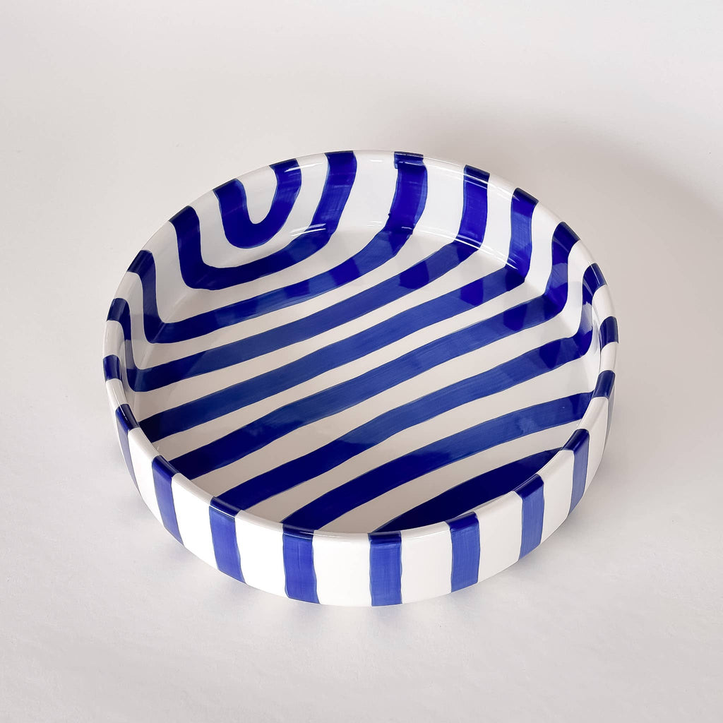 Ceramic bowl with blue and white striped pattern on a light gray background