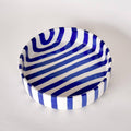 Ceramic bowl with blue and white striped pattern on a light gray background