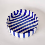 Ceramic bowl with blue and white striped pattern on a light gray background