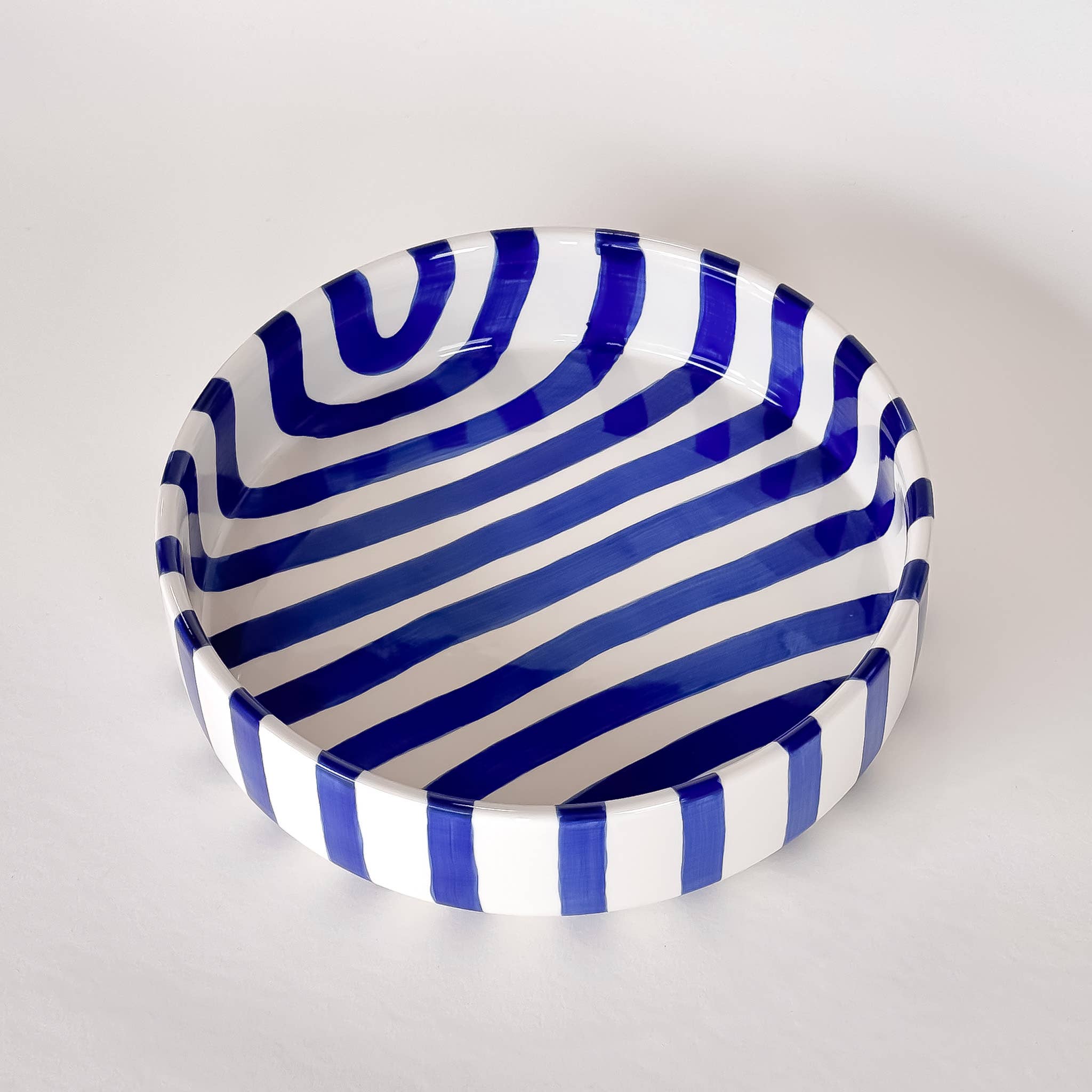 Ceramic bowl with blue and white striped pattern on a light gray background