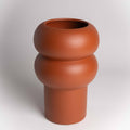 Terracotta-colored vase with a unique design on a white background