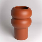 Terracotta-colored vase with a unique design on a white background