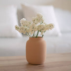 Small terracotta vase with white flowers on a wooden surface