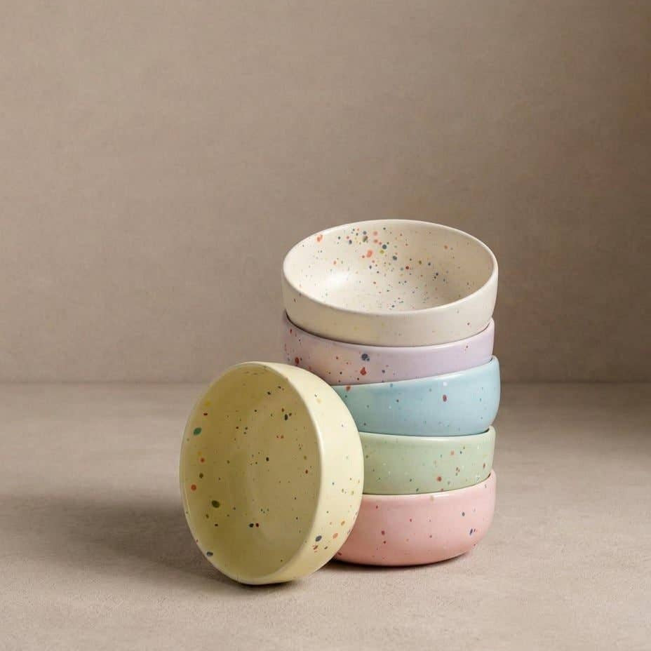 Stack of colorful ceramic bowls on a beige background