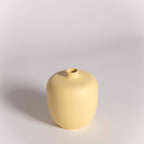 Yellow ceramic vase on a light gray background