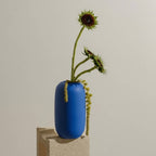 Blue vase with a sunflower against a plain background