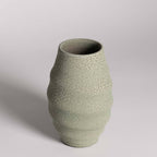 Textured green ceramic vase on a light gray background
